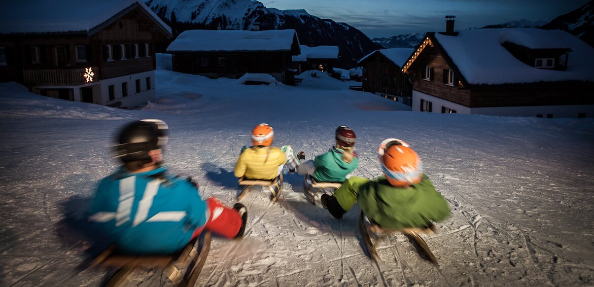 Vier Freunde auf dem Schlitten rodeln über die Nachtrodelbahn Garfrescha in der Silvretta Montafon  | © Silvretta Montafon - Daniel Zangerl