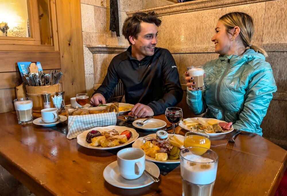 Bergfrühstück - Silvretta Montafon | © Vanessa Strauch - Silvretta Montafon Ein Pärchen sitzt beim Bergfrühstück bei gedecktem Tisch in einer Berghütte. | © Vanessa Strauch - Silvretta Montafon
