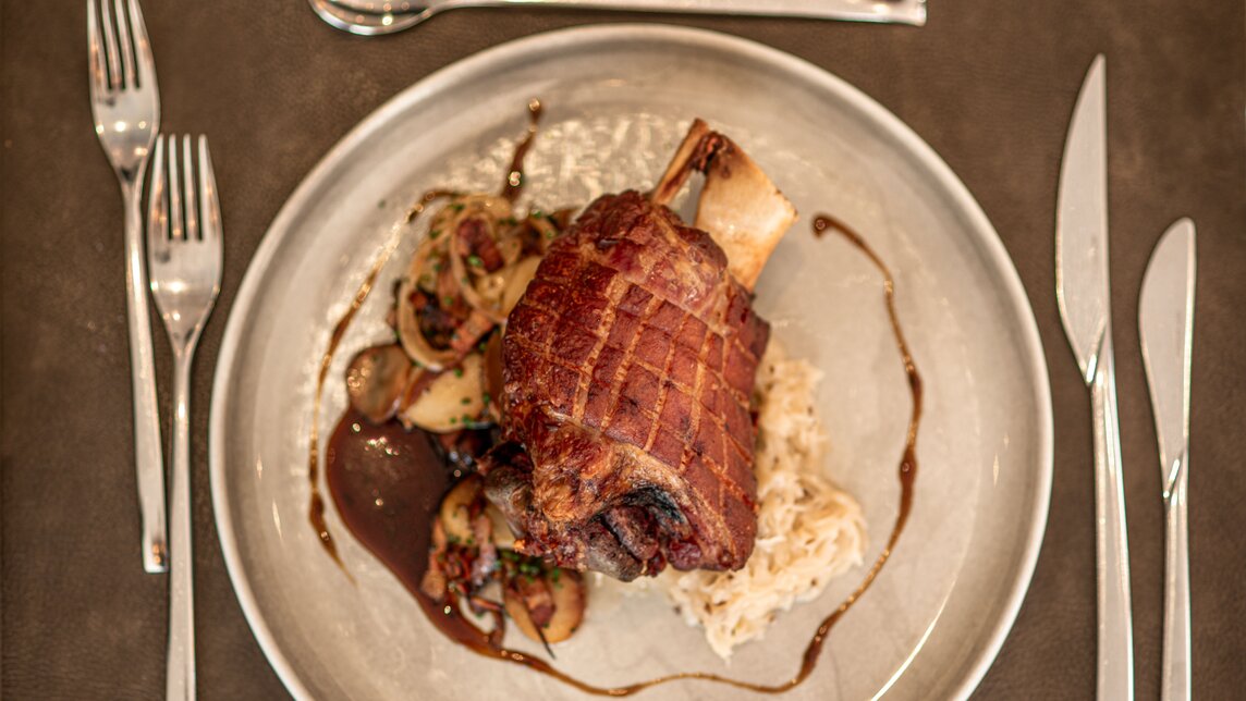 Haxe im Simons - Silvretta Montafon | © Silvretta Montafon - Mara Baues Ein Teller mit Schweinshaxe in Simons Alpenbrasserie im Sporthotel Silvretta Montafon. | © Silvretta Montafon - Mara Baues