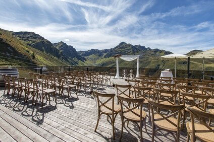 Hochzeit auf der VINNOVA in der Silvretta Montafon | © Silvretta Montafon - Patrick Säly Dekorierter Traubogen und Bestuhlung für eine Hochzeit auf der Terrasse der VINNOVA mit Berge im Hintergrund | © Silvretta Montafon - Patrick Säly