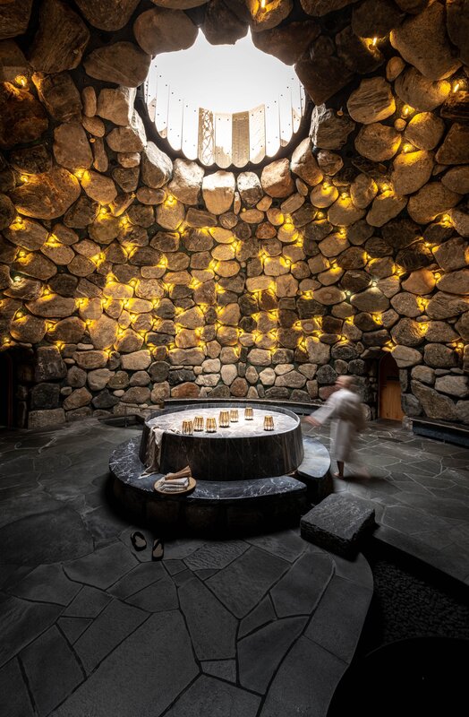 Tepidarium im Gold Spa im Sporthotel Silvretta Montafon | © Silvretta Montafon - blateral Eine Frau läuft durch das Tepidarium, welches in goldenes Licht getaucht ist mit einem Loch in der Decke. | © Silvretta Montafon - blateral