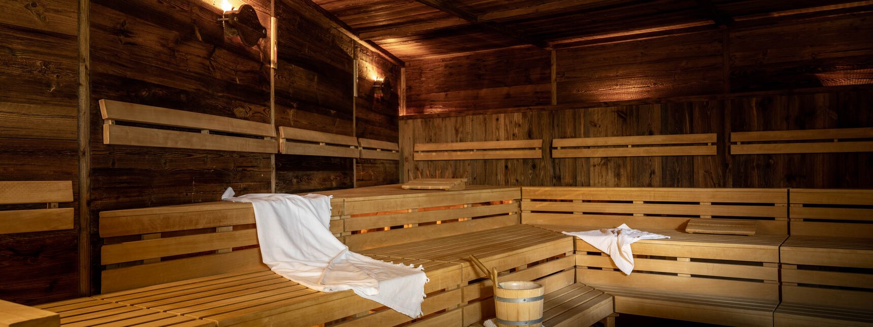 Gold Spa im Sporthotel Silvretta Montafon | © Silvretta Montafon - blateral Eine finnische Sauna komplett in Holz mit Sitzbänken und einem weißen Handtuch | © Silvretta Montafon - blateral