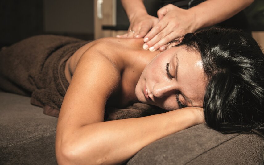 Massage im Sporthotel Silvretta Montafon | © Silvretta Montafon Eine dunkelhaarige Frau liegt auf einer Massageliege und bekommt eine Rückenmassage | © Silvretta Montafon