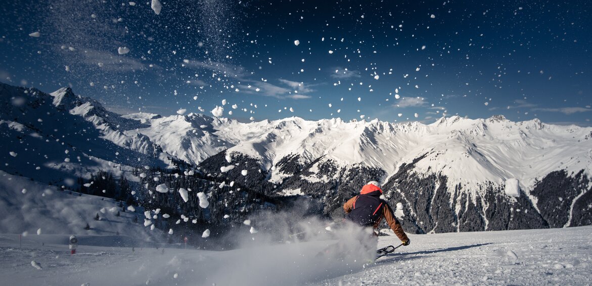 Ein Skifahrer auf der Piste und spritzender Schnee im Vordergrund. | © Silvretta Montafon - Daniel Hug